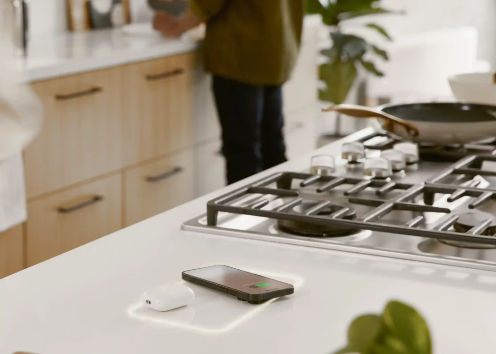 Qi smart home technology charging inset, by freepower, on a countertop, charging a phone while people cook.