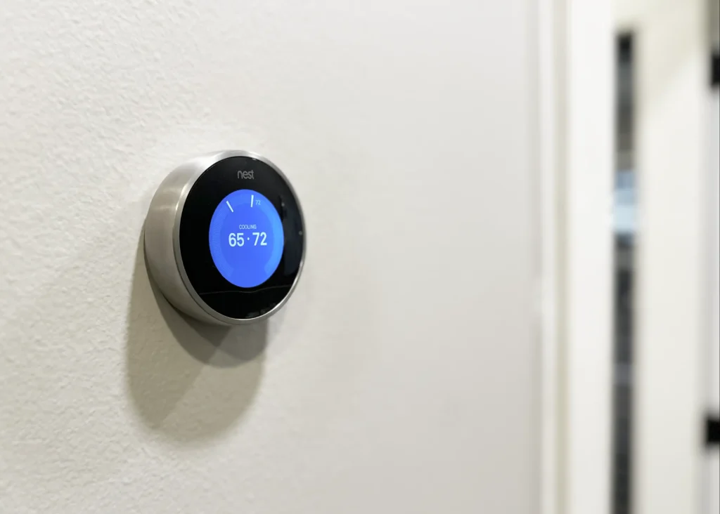 Nest learning smart home technology thermostat installed on a wall.